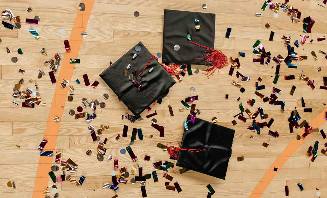 A gymnasium floor with confetti and Graduation Caps. Photo by Pavel Danilyuk on Pexels