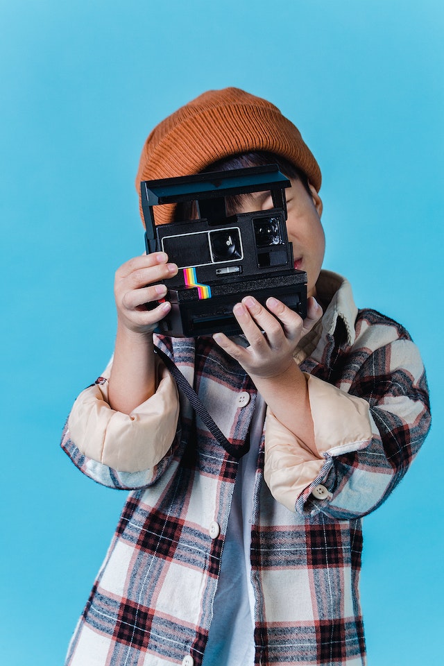 A boy holding a camera ready to take a picture. Photo by: pexels-amina-filkins-5560472