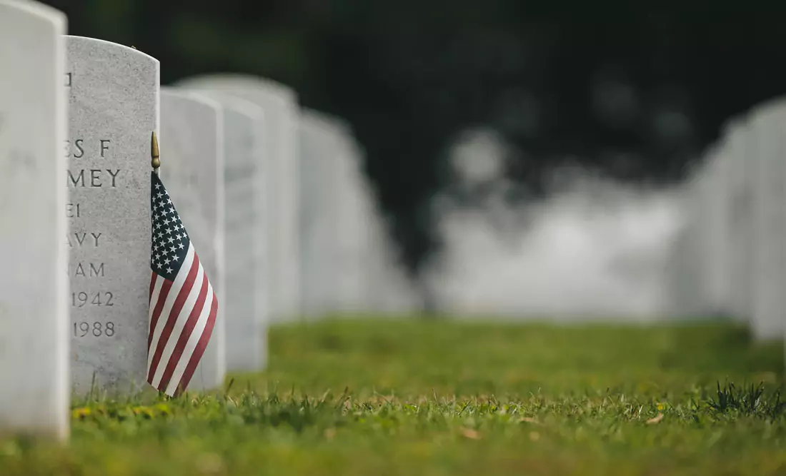 A military grave in Chattanooga TN National Cemetery with an American flag. Photo by Chad Madden on Unsplash.