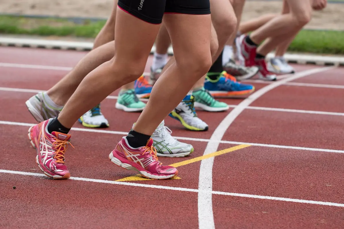 Track and field race with a closeup of runners legs and shoes. Photo by Snapwire.