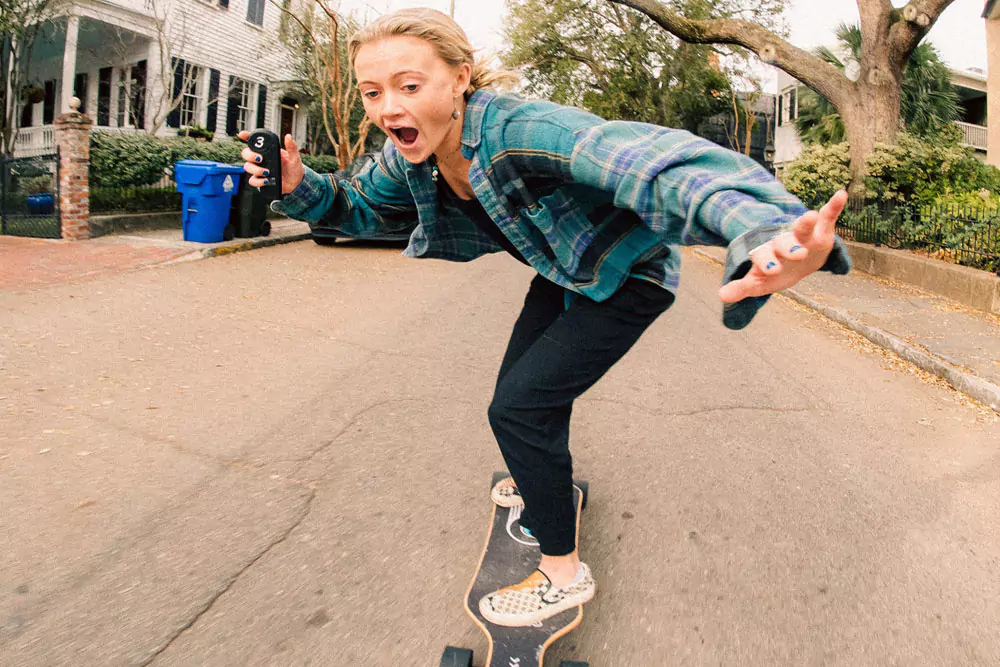 Happy girl on a skateboard cruising down the street. Photo by Trent Palmer on Unsplash