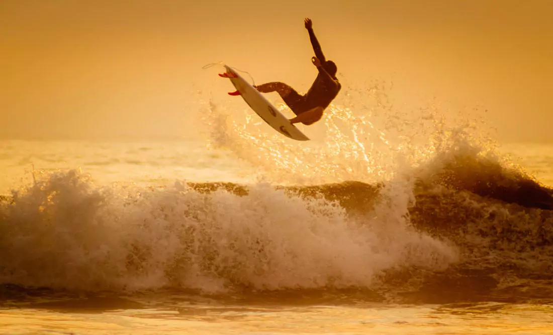 Man on a surfboard catching air on a wave. Photo by Fernando muñoz on Unsplash
